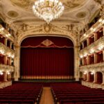 Salle de théâtre à l'italienne restaurée avec balcons dorés et rideau rouge
